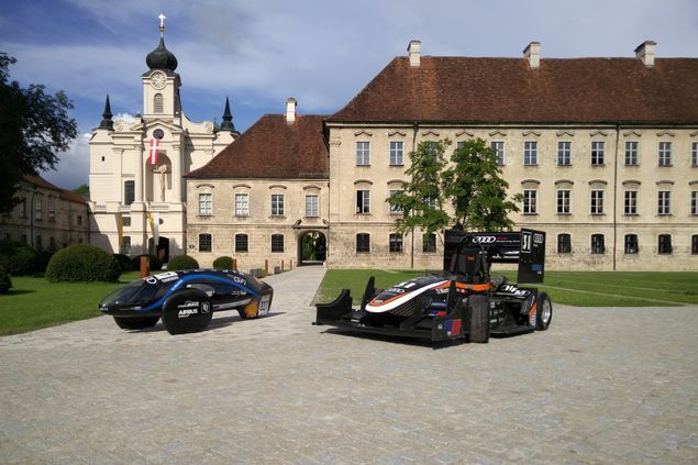 Ein Elektrofahrzeug und ein Rennwagen der Studierendeninitiative „TUfast“ vor dem Akademiezentrum