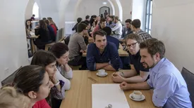 Conference guests sitting at tables in the arched hall of the TUM Science and Study Center Raitenhaslach.