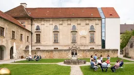 Der Prälatengarten im TUM Akademiezentrum mit Sitzgruppen, im Hintergrund der historische Festsaaltrakt mit modernem Anbau