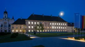 Front view of the TUM Science and Study Center Raitenhaslach with brightly lit windows at night.