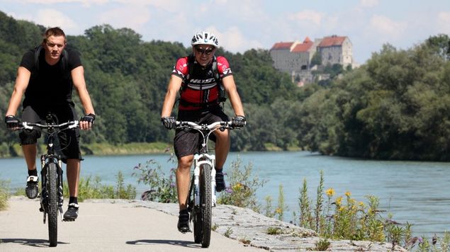 Two cyclists on the Salzach Cycle Path, Burghausen Castle in the background.