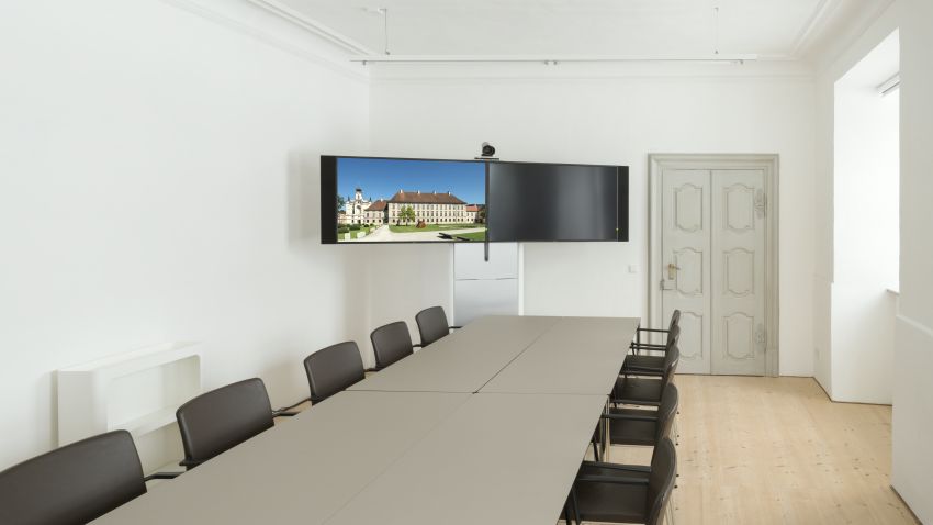 Seminarraum A015 mit Videokonferenzsystem im Hintergrund und Blockbestuhlung im TUM Akademiezentrum Raitenhaslach